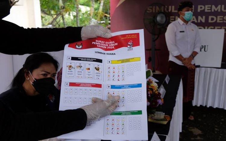 Anggota KPPS menunjukkan surat suara kepada pemilih saat simulasi pemungutan dan penghitungan suara dengan desain surat suara dan formulir yang disederhanakan dalam persiapan penyelenggaraan Pemilu serentak tahun 2024 di Kantor KPU Provinsi Bali, Denpasar, Bali, Kamis (2/12/2021). Foto: Antara