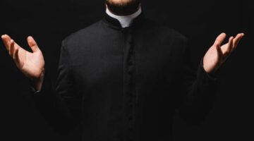 cropped view of priest with outstretched hands isolated on black