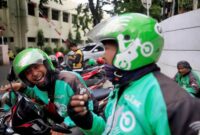 A Go-Jek driver shares jokes with his colleague while waiting for customers along a street in Jakarta, Indonesia, December 15, 2017. REUTERS/Beawiharta/File Photo