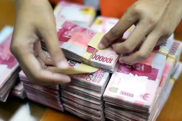 A clerk arranges bundles of Indonesian 100,000 rupiah banknotes at a currency exchange office in Jakarta, Indonesia, on Wednesday, Sept. 9, 2015. The Indonesian stock index is Asia's worst-performing national benchmark this year and the last time the rupiah was this weak it helped topple then-leader Suharto in 1998. Photographer: Dimas Ardian/Bloomberg